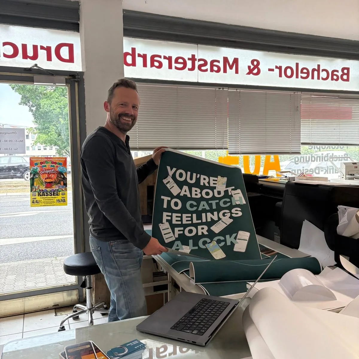 Marcus in the workshop, holding a sign that says: You're about to catch feelings for a lock