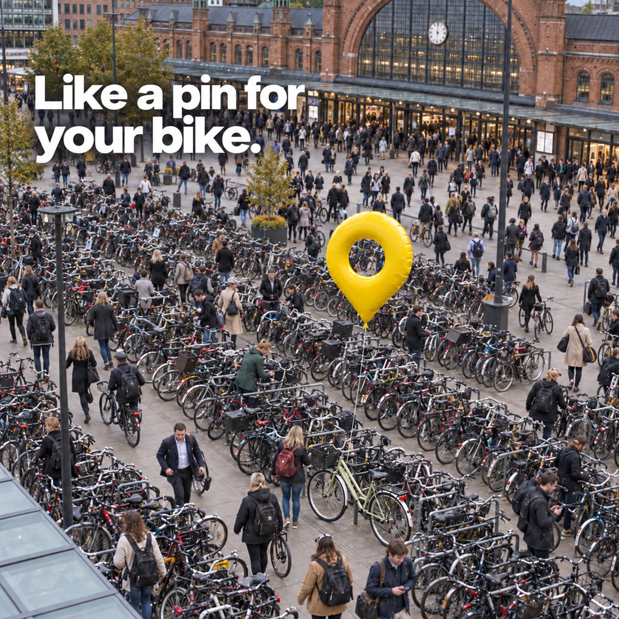 Like a pin for your bike. A yellow location-pin balloon marks one bicycle among hundreds outside a busy Copenhagen station.